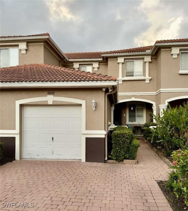 9808 Roundstone Cir, Fort Myers, FL 33967 - view of front of property featuring stucco siding, decorative driveway, an attached garage, and a tile roof