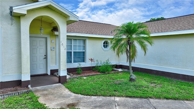 1612 Covington Meadows Cir, Lehigh Acres, FL 33936 - entrance to property with stucco siding, a shingled roof, and a lawn
