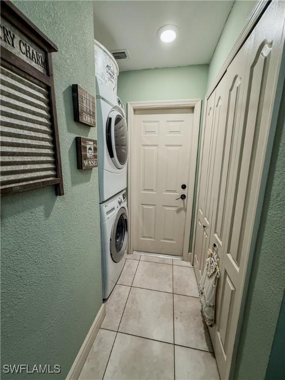 1700 E 15th St, Lehigh Acres, FL 33972 - laundry room with stacked washer / drying machine, light tile patterned flooring, and a textured wall