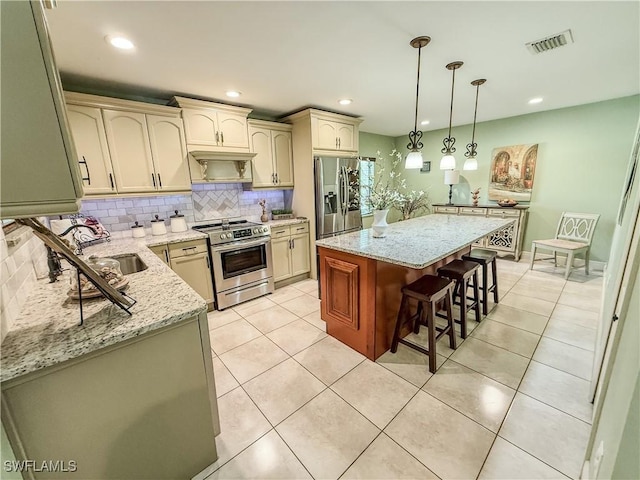 1700 E 15th St, Lehigh Acres, FL 33972 - kitchen featuring stainless steel appliances, decorative backsplash, decorative light fixtures, a breakfast bar area, and light stone countertops