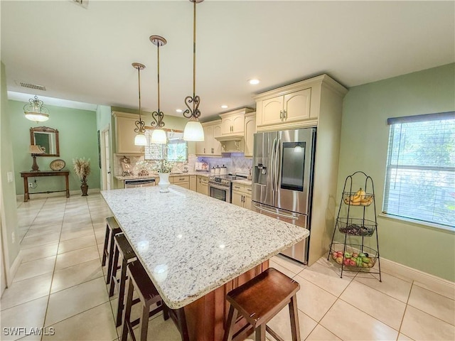 1700 E 15th St, Lehigh Acres, FL 33972 - kitchen featuring stainless steel appliances, cream cabinetry, decorative backsplash, light tile patterned floors, and light stone countertops