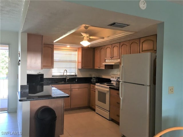 834 SE 46th St Unit 2A, Cape Coral, FL 33904 - kitchen featuring white appliances, dark countertops, under cabinet range hood, a raised ceiling, and a ceiling fan