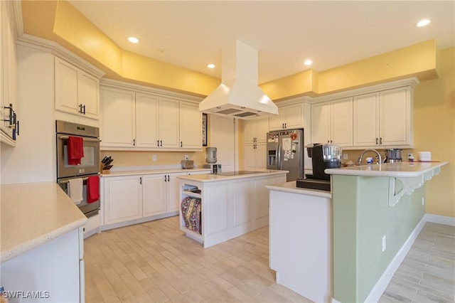 19801 N River Rd, Alva, FL 33920 - kitchen with appliances with stainless steel finishes, island range hood, a peninsula, light countertops, and light wood finished floors