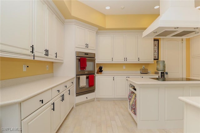 19801 N River Rd, Alva, FL 33920 - kitchen featuring stainless steel double oven, island exhaust hood, light countertops, light wood-type flooring, and black electric cooktop