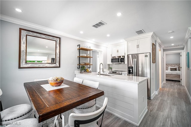 778 98th Ave N, Naples, FL 34108 - kitchen featuring appliances with stainless steel finishes, white cabinets, light wood-type flooring, crown molding, and recessed lighting
