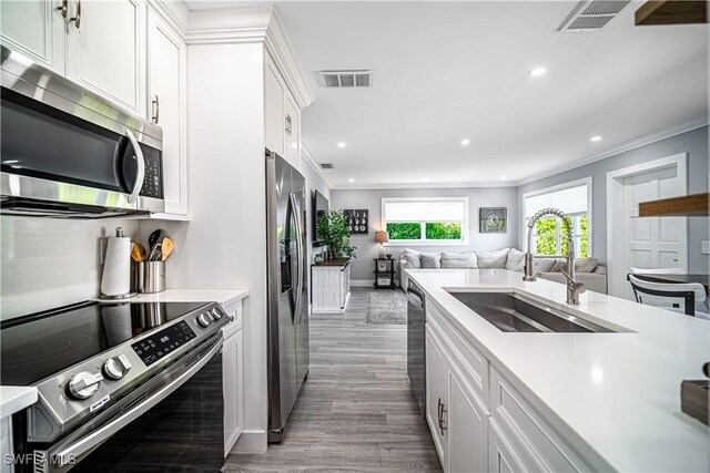 778 98th Ave N, Naples, FL 34108 - kitchen with stainless steel appliances, open floor plan, light countertops, crown molding, and wood finished floors