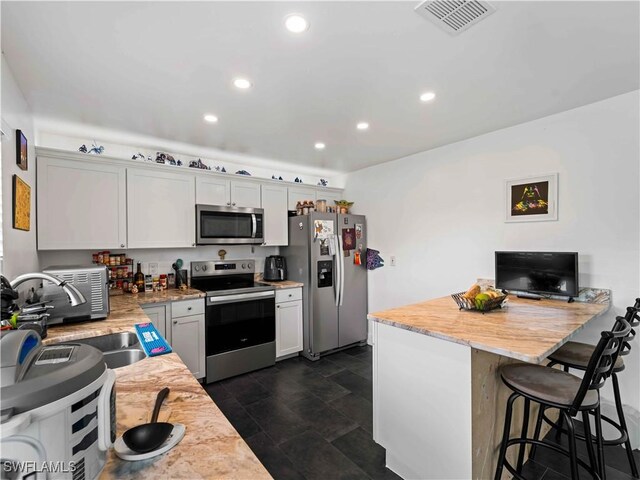 17577 Moorfield Dr, Fort Myers, FL 33908 - kitchen with stainless steel appliances, a kitchen breakfast bar, white cabinets, recessed lighting, and a peninsula