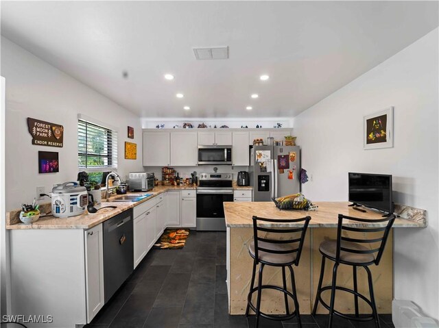 17577 Moorfield Dr, Fort Myers, FL 33908 - kitchen with stainless steel appliances, a peninsula, a breakfast bar, white cabinets, and recessed lighting