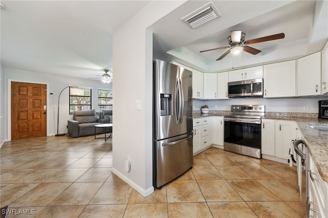 1831 SE 6th St, Cape Coral, FL 33990 - kitchen with stainless steel appliances, a ceiling fan, light stone counters, white cabinets, and light tile patterned floors