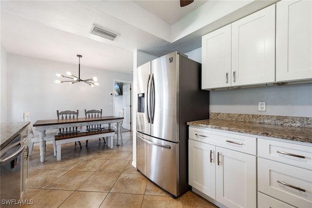 1831 SE 6th St, Cape Coral, FL 33990 - kitchen with stainless steel appliances, a chandelier, white cabinetry, light stone countertops, and decorative light fixtures