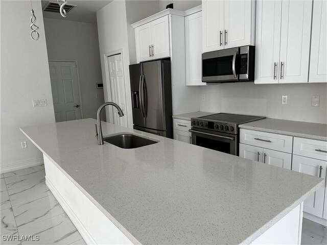 904 James Ave, Lehigh Acres, FL 33936 - kitchen featuring appliances with stainless steel finishes, light marble finish floors, white cabinetry, an island with sink, and light stone counters