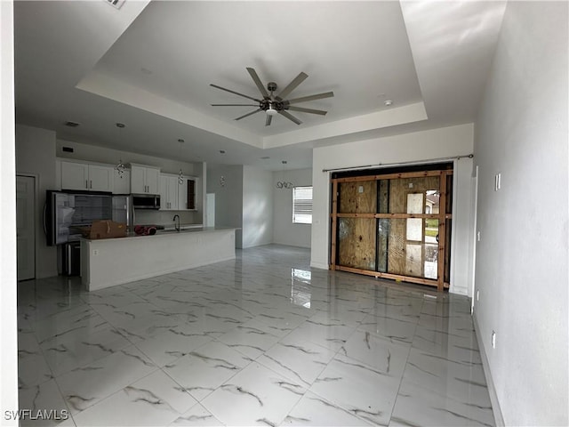 904 James Ave, Lehigh Acres, FL 33936 - unfurnished living room featuring a tray ceiling and a ceiling fan