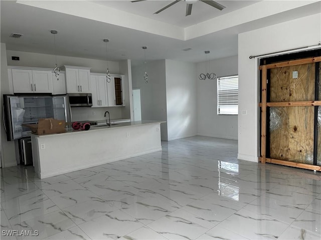 904 James Ave, Lehigh Acres, FL 33936 - kitchen with stainless steel microwave, an island with sink, ceiling fan, white cabinetry, and pendant lighting