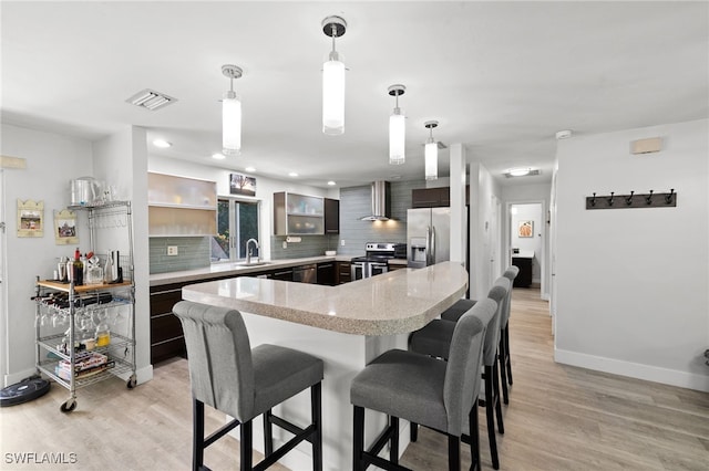 134 Palm River Blvd, Naples, FL 34110 - kitchen featuring stainless steel appliances, wall chimney range hood, decorative backsplash, light wood-style floors, and recessed lighting