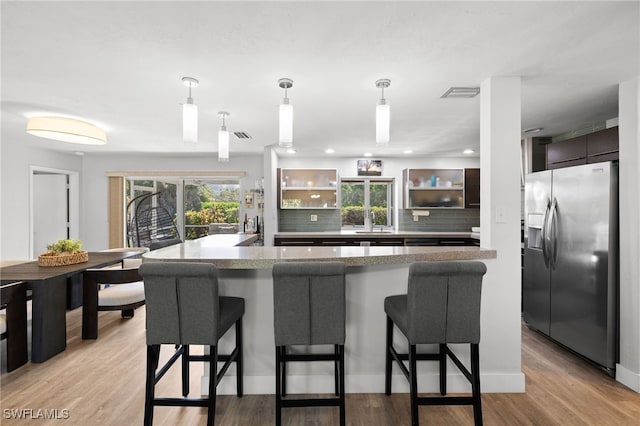134 Palm River Blvd, Naples, FL 34110 - kitchen featuring stainless steel refrigerator with ice dispenser, a kitchen breakfast bar, modern cabinets, tasteful backsplash, and light wood finished floors