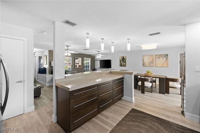 134 Palm River Blvd, Naples, FL 34110 - kitchen with dark brown cabinetry, open floor plan, light countertops, pendant lighting, and light wood-type flooring