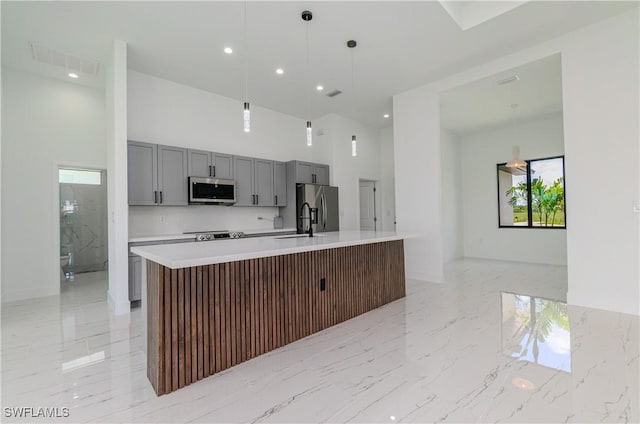 1144 Monday St, Labelle, FL 33935 - kitchen with stainless steel appliances, gray cabinetry, light countertops, a towering ceiling, and an island with sink