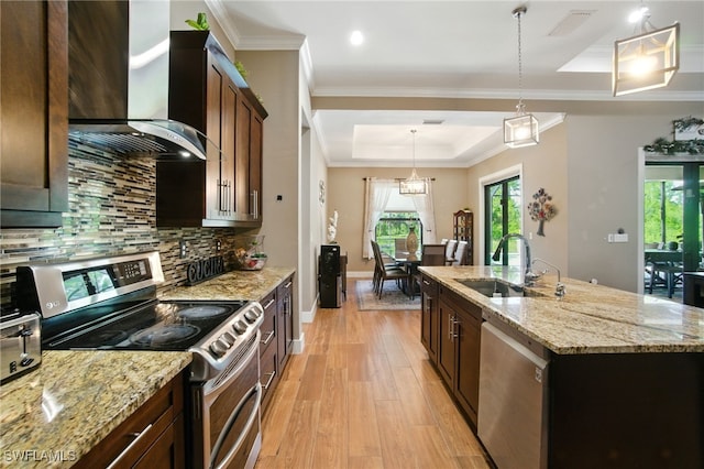 1912 Jung Blvd E, Naples, FL 34120 - kitchen featuring appliances with stainless steel finishes, wall chimney exhaust hood, an island with sink, decorative backsplash, and ornamental molding