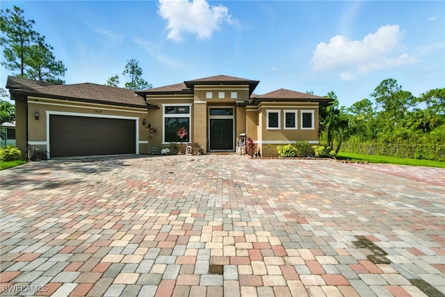 1912 Jung Blvd E, Naples, FL 34120 - prairie-style house with stucco siding, decorative driveway, and a garage