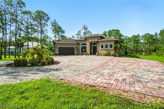 1912 Jung Blvd E, Naples, FL 34120 - prairie-style house with an attached garage, decorative driveway, and stucco siding