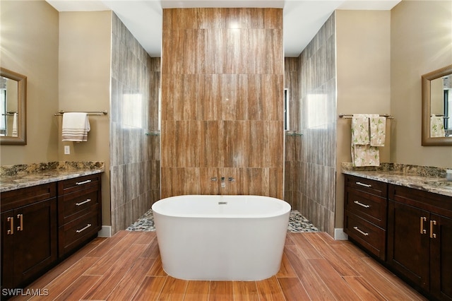 1912 Jung Blvd E, Naples, FL 34120 - bathroom with healthy amount of natural light, a freestanding tub, wood finished floors, two vanities, and tile walls