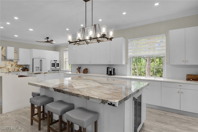 5040 Yacht Harbor Cir Unit 6, Naples, FL 34112 - kitchen featuring a center island, high end refrigerator, ornamental molding, recessed lighting, and decorative backsplash