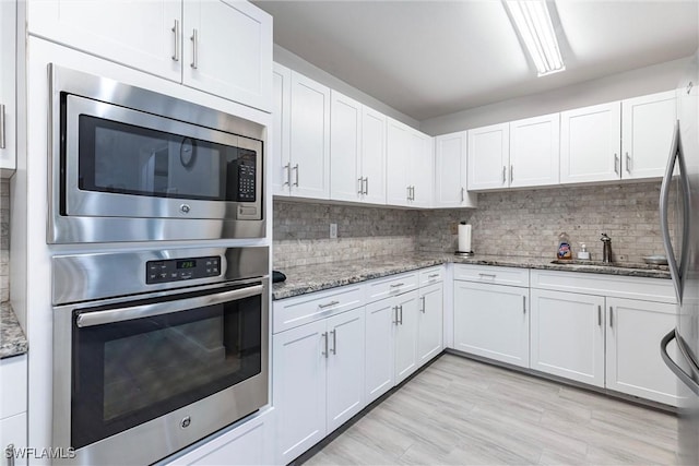 6769 Berwick Pl, Naples, FL 34104 - kitchen with appliances with stainless steel finishes, white cabinets, decorative backsplash, and light stone countertops