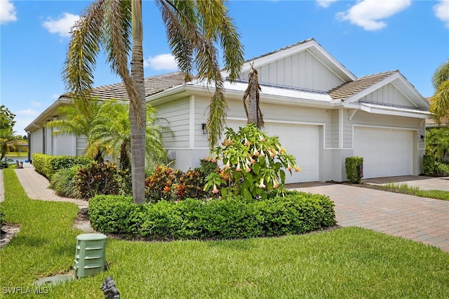 14803 Edgewater Cir, Naples, FL 34114 - view of property exterior featuring a garage, driveway, board and batten siding, and a lawn