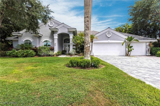 4372 Bittern Ct, Naples, FL 34119 - view of front facade with decorative driveway, stucco siding, a front lawn, and a garage