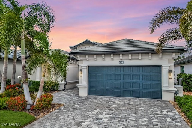 10082 Palazzo Dr, Naples, FL 34119 - view of front of house featuring decorative driveway, an attached garage, stucco siding, and a tile roof
