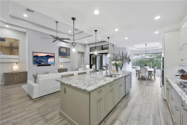 10082 Palazzo Dr, Naples, FL 34119 - kitchen featuring stainless steel dishwasher, a tray ceiling, a kitchen island with sink, wood finish floors, and a ceiling fan