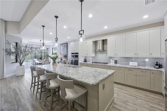 10082 Palazzo Dr, Naples, FL 34119 - kitchen featuring wall chimney range hood, appliances with stainless steel finishes, a center island with sink, backsplash, and recessed lighting
