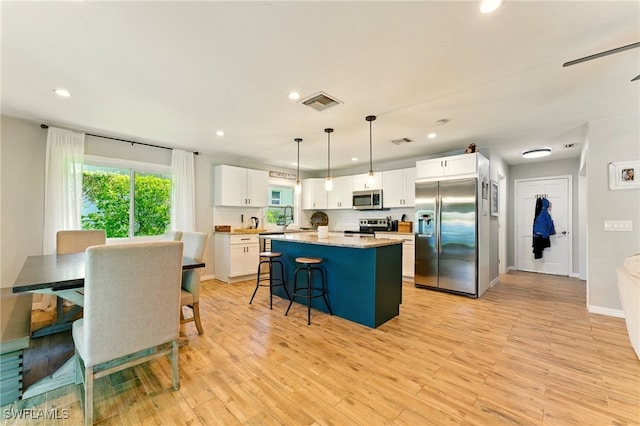 2491 43rd St SW, Naples, FL 34116 - kitchen with stainless steel appliances, white cabinets, recessed lighting, a kitchen island, and light wood-type flooring