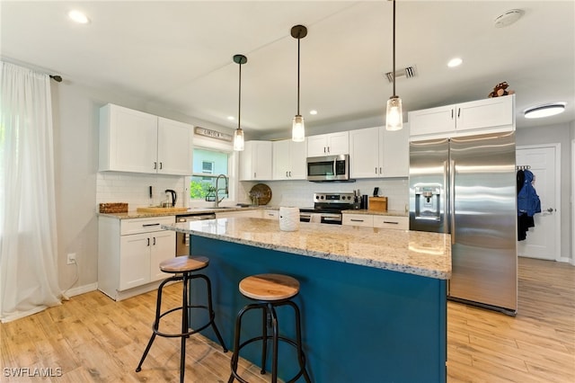 2491 43rd St SW, Naples, FL 34116 - kitchen featuring appliances with stainless steel finishes, light wood-type flooring, decorative backsplash, white cabinets, and recessed lighting