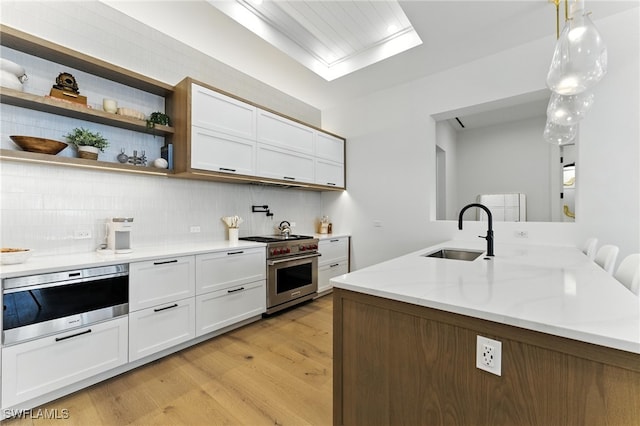 201 8th St S Unit 208, Naples, FL 34102 - kitchen featuring premium range, light wood-style flooring, decorative backsplash, white cabinets, and pendant lighting