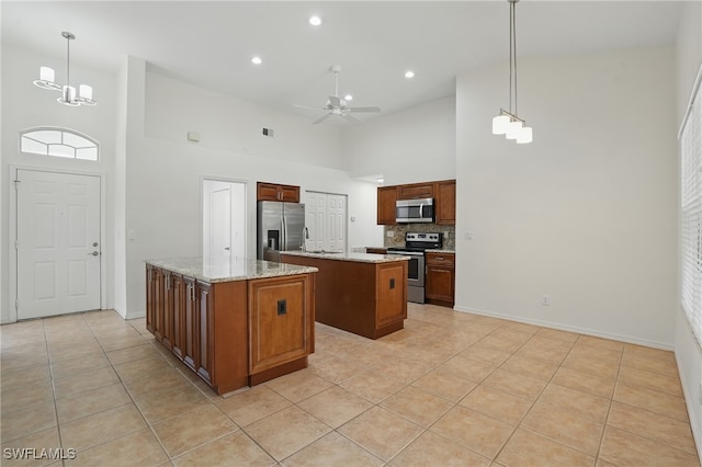 6643 Craven Hill Way, Naples, FL 34104 - kitchen featuring appliances with stainless steel finishes, a center island, a high ceiling, light tile patterned floors, and decorative backsplash