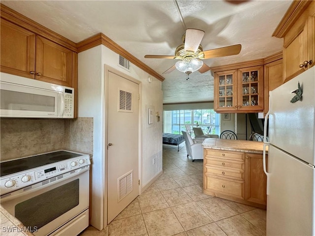 377 Vanderbilt Beach Rd Unit 103, Naples, FL 34108 - kitchen featuring white appliances, tile counters, brown cabinetry, light tile patterned flooring, and glass insert cabinets