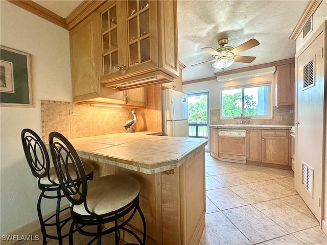 377 Vanderbilt Beach Rd Unit 103, Naples, FL 34108 - kitchen featuring freestanding refrigerator, dishwashing machine, a breakfast bar, decorative backsplash, and a ceiling fan
