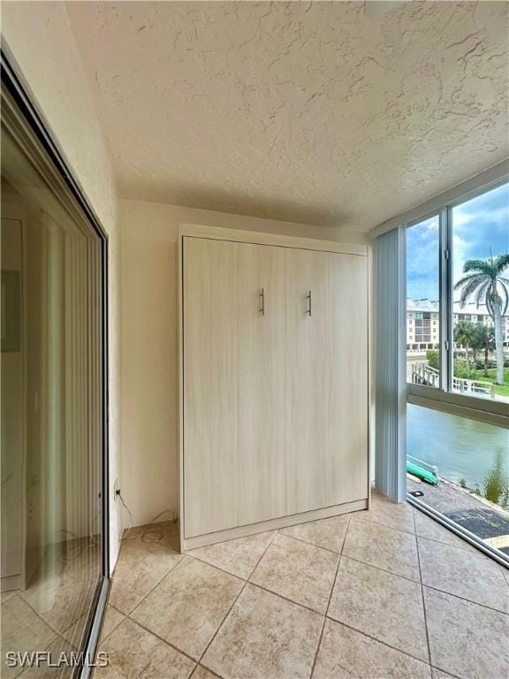 377 Vanderbilt Beach Rd Unit 103, Naples, FL 34108 - unfurnished bedroom with a textured ceiling and light tile patterned floors