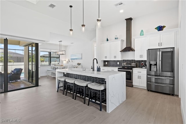 301 NW 36th Ave, Cape Coral, FL 33993 - kitchen with appliances with stainless steel finishes, range hood, a kitchen bar, light wood-style flooring, and white cabinets