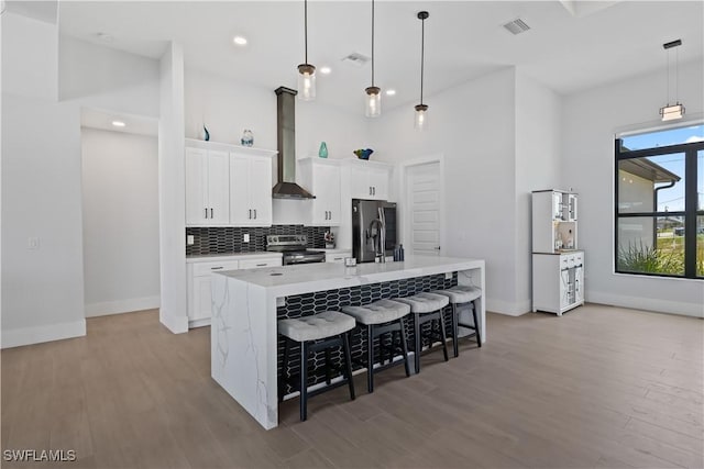 301 NW 36th Ave, Cape Coral, FL 33993 - kitchen with wall chimney exhaust hood, appliances with stainless steel finishes, an island with sink, wood finished floors, and recessed lighting