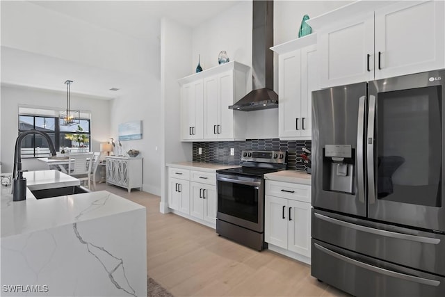 301 NW 36th Ave, Cape Coral, FL 33993 - kitchen with stainless steel appliances, wall chimney exhaust hood, white cabinetry, decorative backsplash, and light wood-style flooring