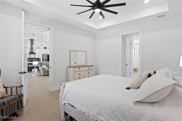 301 NW 36th Ave, Cape Coral, FL 33993 - bedroom featuring stainless steel fridge with ice dispenser, light wood-style flooring, recessed lighting, a tray ceiling, and connected bathroom