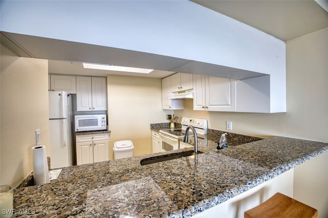 1900 Virginia Ave Unit 102, Fort Myers, FL 33901 - kitchen featuring white appliances, dark stone countertops, a peninsula, and under cabinet range hood
