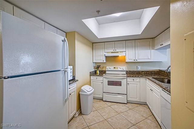 1900 Virginia Ave Unit 102, Fort Myers, FL 33901 - kitchen featuring white appliances, under cabinet range hood, a tray ceiling, light tile patterned flooring, and dark stone counters