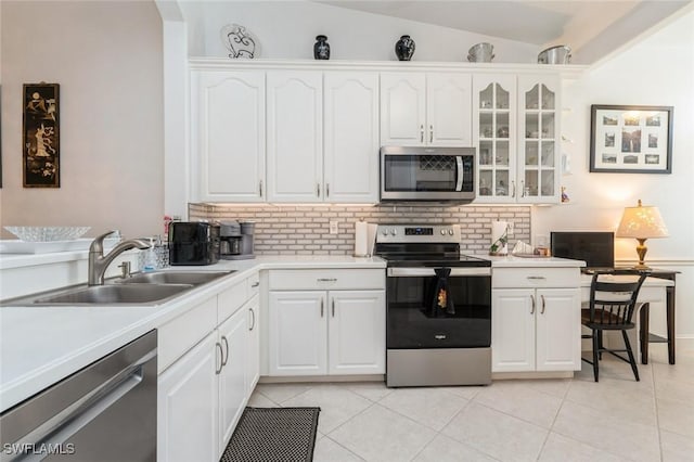 15029 Toscana Way, Naples, FL 34120 - kitchen with stainless steel appliances, decorative backsplash, light tile patterned floors, glass insert cabinets, and lofted ceiling