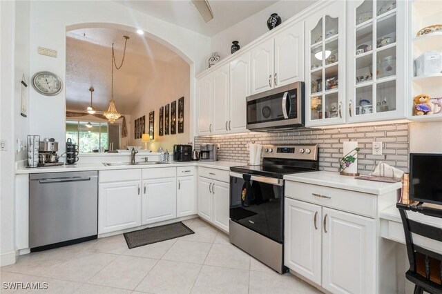 15029 Toscana Way, Naples, FL 34120 - kitchen featuring stainless steel appliances, backsplash, glass insert cabinets, arched walkways, and white cabinetry