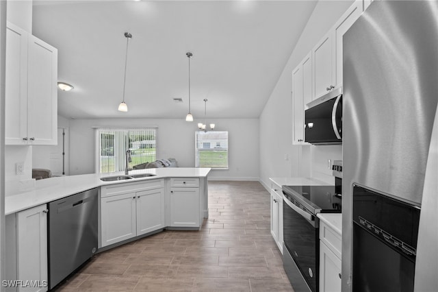 2801 50th St SW, Lehigh Acres, FL 33976 - kitchen with stainless steel appliances, a peninsula, white cabinets, vaulted ceiling, and light countertops