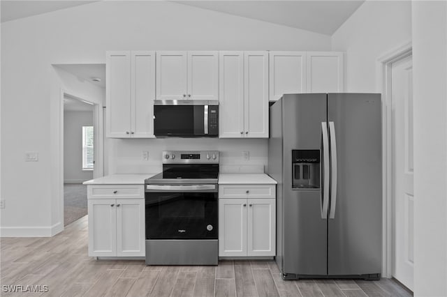 2801 50th St SW, Lehigh Acres, FL 33976 - kitchen featuring appliances with stainless steel finishes, vaulted ceiling, light countertops, white cabinets, and light wood-style flooring