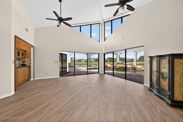 8060 Glenfinnan Cir, Fort Myers, FL 33912 - unfurnished living room with a ceiling fan, a towering ceiling, healthy amount of natural light, wood finished floors, and a water view